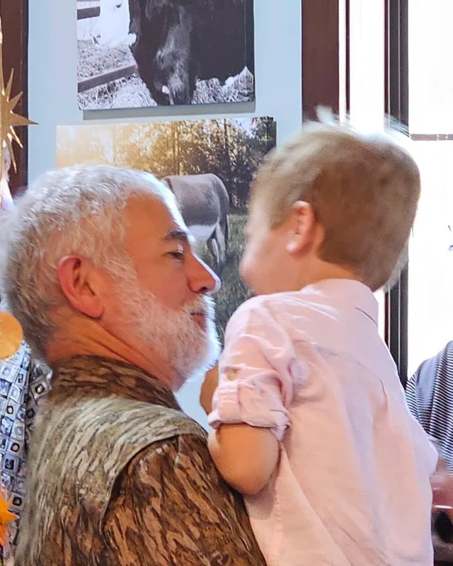 Dr. Thompson holding a young child at his 35th anniversary celebration